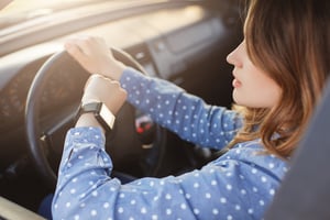 woman driving a car and looking at watch