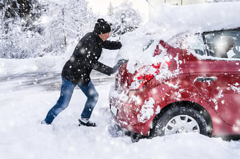 Man pushing car stuck in snow