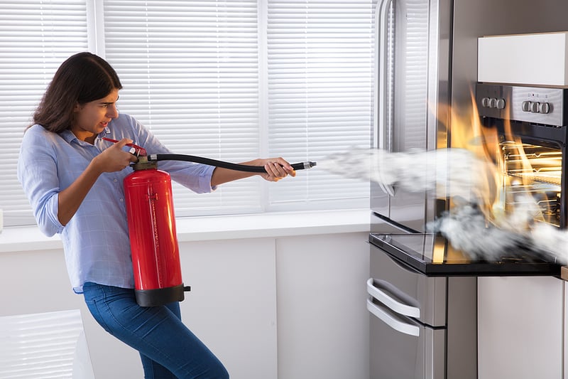 Woman using fire extinguisher in kitchen