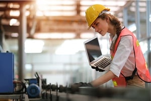 Woman wearing hard hat and holding a laptop